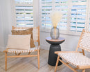 Bundle of dried natural white baby's breath in a clear glass vase, displayed in a bright modern room with woven wooden.