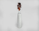 Single bunch of dried red yarrow flowers in a tall white ceramic vase, natural bulk bouquet.