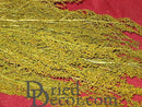 Bulk dried Sweet Annie flower bunches with natural yellow-green color on red background.