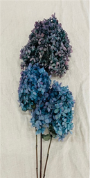 Bulk dried natural blue hydrangea bunches with stems arranged on fabric background.