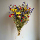 A dried flower bouquet featuring a variety of colors and types of flowers, tied together at the base with string.