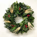 A round wreath decoration featuring a variety of greenery and dried wheat accents, with red and green berries.