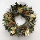 A circular wreath decorated with basil salal leaves, gold painted salal leaves, cedar, and pine cones.
