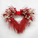 A handmade decorative wreath featuring red quail brush, red canella berries, red paper rose, ammobium, and larkspur.