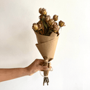 Hand holding a bulk bunch of natural dried Spray Rose flowers wrapped in brown kraft paper.