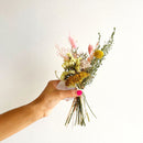 Hand holding a bouquet of flowers against a white background