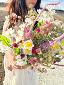 Dried dogwood and yellow daffodils bouquet with pink and white wildflowers, natural bulk arrangement.