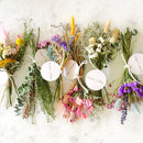 Bouquets of dried flowers with visible brand labels on a textured white background