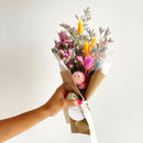 Bouquet of flowers held by a hand with a plain background