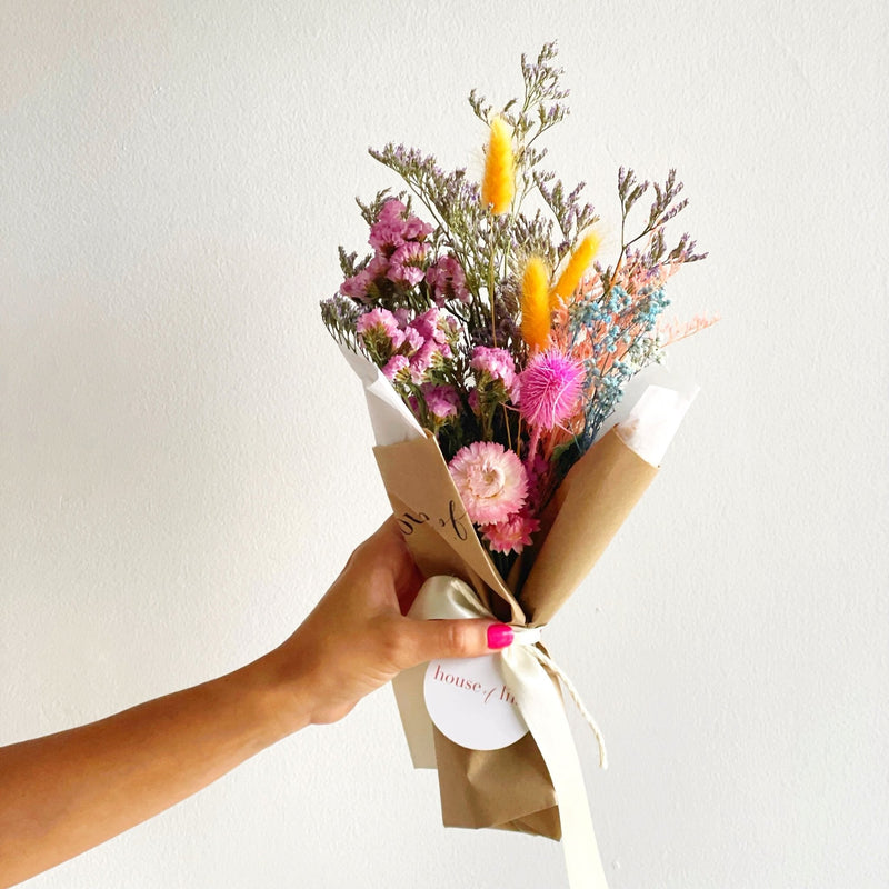 Bouquet of flowers held by a hand with a plain background