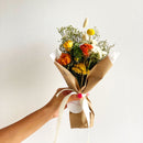 Orange yellow dried flower bouquet with natural green fillers wrapped in brown paper, tied with cream ribbon, wholesale bulk .