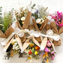 Assorted dried flower bouquets wrapped in natural brown paper with white ribbon, featuring colorful blooms in bulk wholesale .