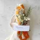 Decorative place card with dried flowers and orange slices on a marble background