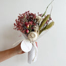 Pink dried flower bundle with natural roses, baby's breath, and assorted wildflowers tied with white fabric ribbon for.