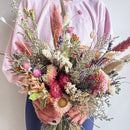 Person holding a vibrant bouquet of flowers against a neutral background
