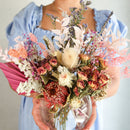 Person holding a vibrant bouquet of flowers with a blurred background