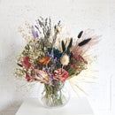 Medium dried flower arrangement in clear glass vase with natural pampas, lavender, and pink blooms.