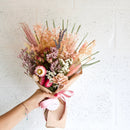 Dried natural flower bouquet with pink, purple, and beige blooms wrapped in brown paper, bulk wholesale style.