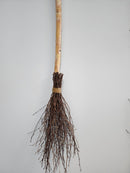 A decorative birch broom with a long handle and twisted birch twigs at the bottom, bound with twine.