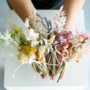 Colorful small dried flower bundles with natural stems arranged for wholesale bulk display.