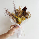 Natural dried flower bundle in bright orange and yellow tones wrapped in white paper for wholesale and bulk purchase.