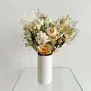 Bouquet of flowers in a white vase on a glass table with a light gray background