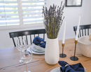 Dried natural Grosso lavender bunch in white vase on dining table with candles and glassware.