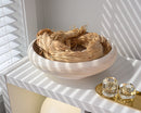 Bulk natural tan dried raffia hank in a light wooden bowl on white shelf with sunlight shadows.