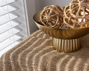 Natural tan jute cloth with coarse weave draped on table, paired with dried decorative wicker balls in gold bowl.