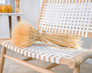 Bulk dried blond wheat sheaves with natural stems laid on a modern woven chair.