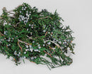 Dried natural juniper mini tips with green foliage and blue berries in bulk wholesale quantity.
