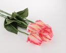 A bouquet of artificial pink cream tulip stems with green leaves on a white background.