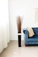 Natural light brown dried Asian willow branches arranged in a tall black vase, wholesale bulk display.