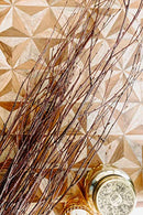 Natural brown dried birch branches arranged in bulk on textured wood surface with decorative jars nearby.