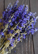 Bundle of dark blue dried larkspur flowers with natural stems on wooden surface, wholesale bulk display.