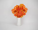 Bundle of dried natural autumn oak leaves in vibrant orange and red shades arranged in a white vase, wholesale bulk display.