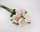 A bunch of artificial peony spray flowers with blush pink petals and green leaves on a white background.