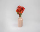Bundle of natural dried red chili peppers in peach ceramic vase, bulk wholesale decor.