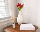 Red dried tulip bundle with green stems in white vase on wooden table, natural wholesale bulk flowers.
