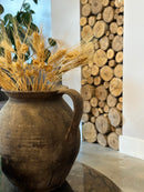 Dried blond wheat bunches arranged in a rustic clay vase, natural decorative bulk display.