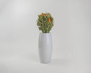 Bulk dried safflower bouquet with natural light green leaves and orange, yellow, and red flowers in a white ceramic vase.