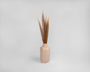 Bundle of natural dried golden pheasant feathers displayed in a beige ceramic vase, wholesale bulk set.