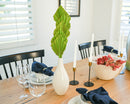 Dried natural green spear palm frond in white vase on wooden dining table with modern decor.