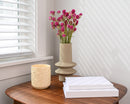 Bulk dried natural globe amaranth hot pink flowers in sculpted beige vase on wood table.