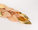 A collection of faux magnolia leaves with rose gold metallic on one side and velvet texture on the other, displayed on a white background.