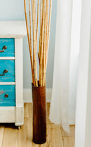 Natural dried river cane bamboo sticks bundled in a tall brown vase for bulk wholesale decor.