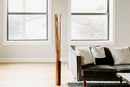 Bundle of tall, dried natural river cane stalks in bulk standing in a modern living room near sofa.