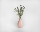 Bulk dried natural light blue globe thistle bunch in blush pink vase against white background.