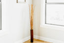 Tall dried natural river cane stems arranged in a dark vase in a bright corner, wholesale bulk pack.