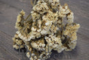 Bulk dried natural white statice sinuata flower bunches on rustic wooden surface.